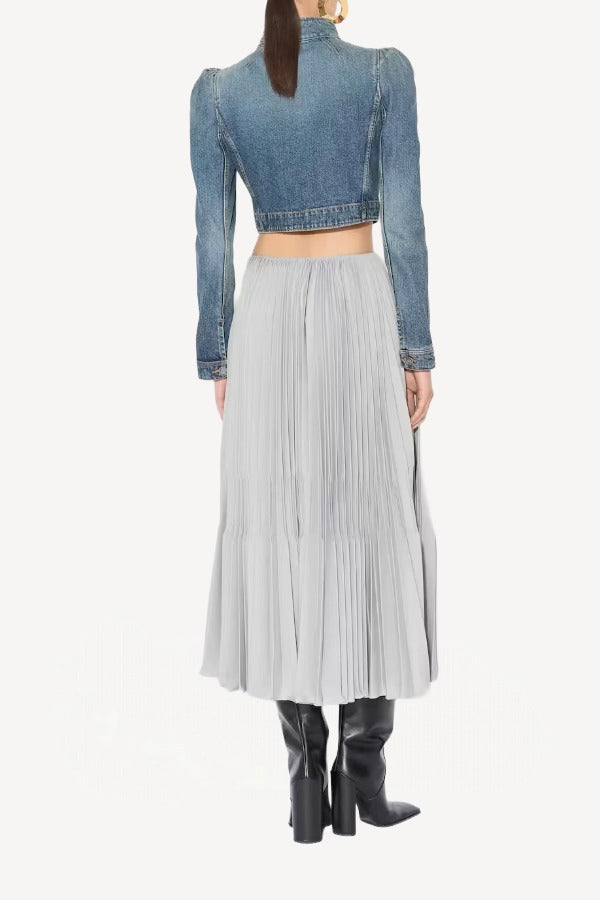 Back view of gris souris pleated skirt on model wearing jean jacket and boots, against a white background.