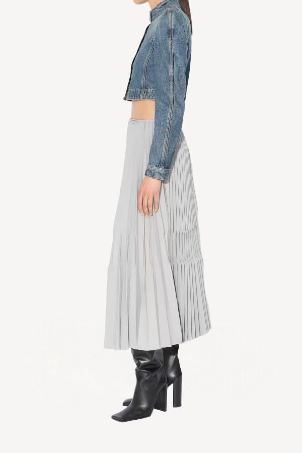 Side view of gris souris pleated skirt on model wearing jean jacket and boots, against a white background.
