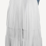 Front closeup of gris souris pleated skirt on model wearing jean jacket, against a white background.