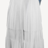 Front closeup of gris souris pleated skirt on model wearing jean jacket, against a white background.