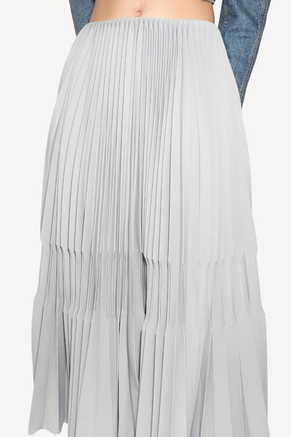Front closeup of gris souris pleated skirt on model wearing jean jacket, against a white background.