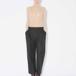 Front view of mastic secondskin bodysuit on model wearing charcoal trousers and heels, against a white background.