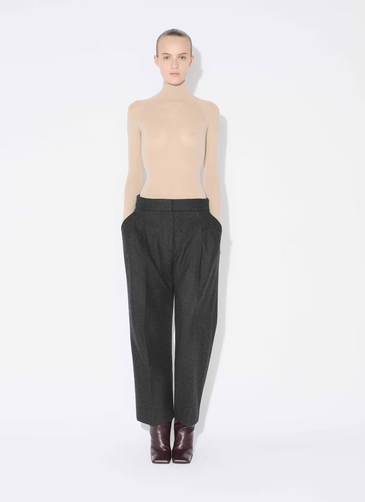 Front view of mastic secondskin bodysuit on model wearing charcoal trousers and heels, against a white background.