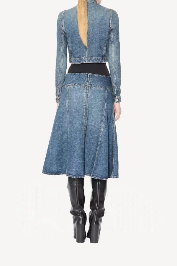 Back view of denim slit skirt on model wearing denim jacket, black bodysuit and boots, against a white background.