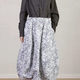 Front view of Bright Flower Carla Skirt on model wearing a dark grey top with black oxfords, against a white background.