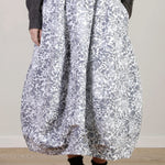 Front closeup view of bright flower carla skirt on model wearing dark grey top with black oxfords, against a white background.