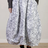 Front closeup view of bright flower carla skirt on model wearing dark grey top with black oxfords, against a white background.