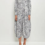 Front view of bright flower letty dress on model wearing white flowers, against a white background