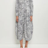 Front view of bright flower letty dress on model wearing white flowers, against a white background