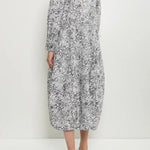 Back view of bright flower letty dress on model wearing white loafers, against a white background.