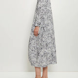Side view of bright flower letty dress on model wearing white loafers, against a white background.