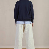 Back view of stone Chloe pants on model wearing stripe shirt, navy sweater and black oxfords, against a white background.