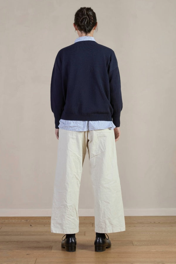 Back view of stone Chloe pants on model wearing stripe shirt, navy sweater and black oxfords, against a white background.