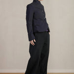 Side view of pinstripe caryl jacket on model wearing black trousers, against a white background.