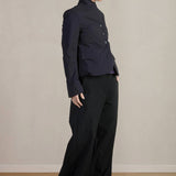 Side view of pinstripe caryl jacket on model wearing black trousers, against a white background.