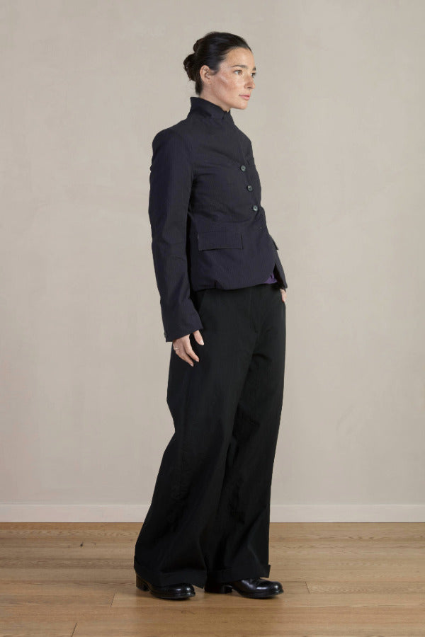 Side view of pinstripe caryl jacket on model wearing black trousers, against a white background.