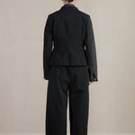 Back view of pinstripe caryl jacket on model wearing black trousers, against a white background.