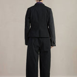 Back view of pinstripe caryl jacket on model wearing black trousers, against a white background.