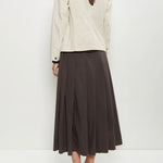 Back view of stone caryl jacket on model wearing brown skirt and black loafers, against a white background.