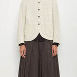 Front view of stone caryl jacket on model wearing brown skirt against a white background.