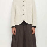 Front view of stone caryl jacket on model wearing brown skirt against a white background.