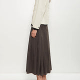 Side view of stone caryl jacket on model wearing brown skirt and black loafers, against a white background.