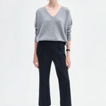 Front view of black cropped flared pant on model wearing grey seater and black boots, against a white background