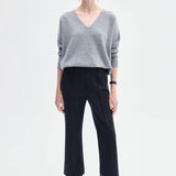 Front view of black cropped flared pant on model wearing grey seater and black boots, against a white background