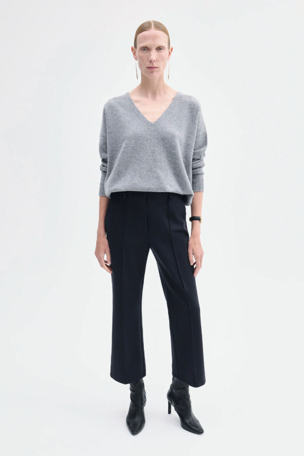 Front view of black cropped flared pant on model wearing grey seater and black boots, against a white background