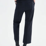 Back view of black cropped flared pant on model wearing grey sweater and black boots, against a white background.