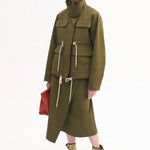 Overhead view of ecru gladiator wrap sandal on model wearing olive jacket and skirt against a white background