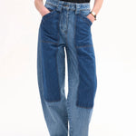 Front closeup view of indigo patchwork pants on model wearing black t-shirt and black sandals, against white background.