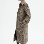 Side view of leopard coat on model wearing black top and flats, against a white background.