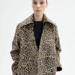 Front view closeup of leopard coat on model wearing black top, against a white background. 