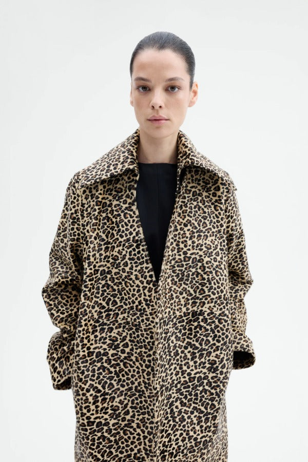 Front view closeup of leopard coat on model wearing black top, against a white background. 