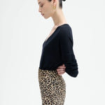 Side view of leopard skirt on model wearing black top, against a white background.