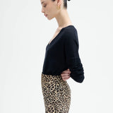 Side view of leopard skirt on model wearing black top, against a white background.