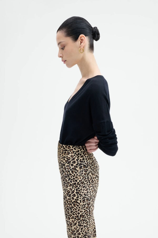 Side view of leopard skirt on model wearing black top, against a white background.