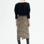 Back view of leopard skirt on model wearing black top and boots, against a white background.