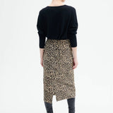 Back view of leopard skirt on model wearing black top and boots, against a white background.