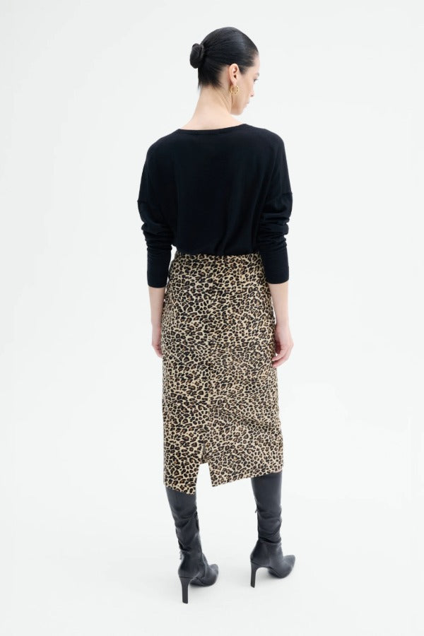 Back view of leopard skirt on model wearing black top and boots, against a white background.