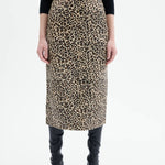 Front closeup view of leopard skirt on model wearing black top and boots, against a white background.