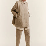 Front slanted view of oatmeal tatiana jacket on model wearing khaki pants and white clogs, against a white background.
