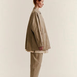 Side view of oatmeal tatiana jacket on model wearing khaki pants and white clogs, against a white background.