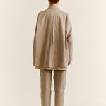 Back view of oatmeal tatiana jacket on model wearing khaki pants and white clogs, against a white background.
