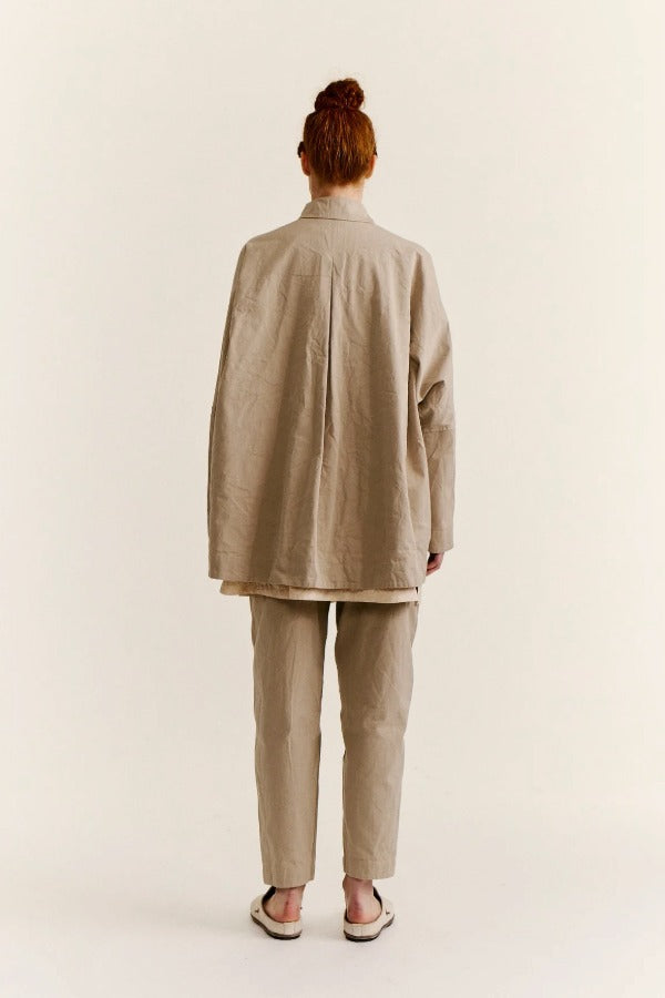 Back view of oatmeal tatiana jacket on model wearing khaki pants and white clogs, against a white background.