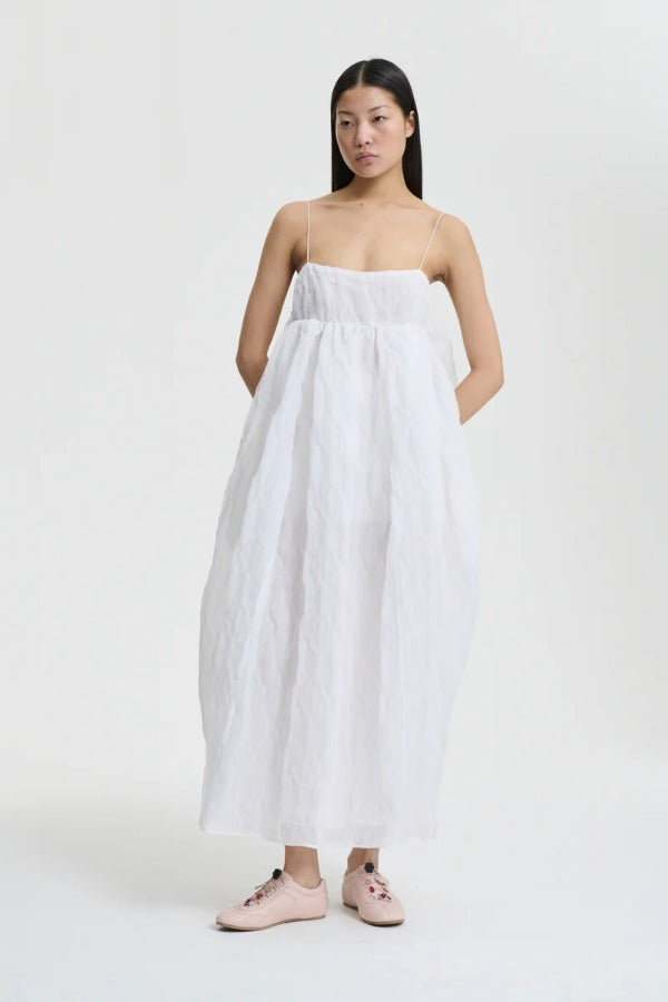 Front view of white vilma dress on model wearing pink sneakers, against a white background.