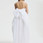 Back view of white vilma dress on model wearing pink sneakers, against a white background.