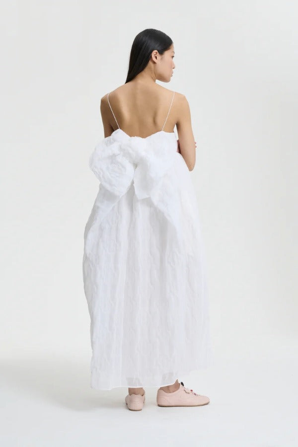 Back view of white vilma dress on model wearing pink sneakers, against a white background.