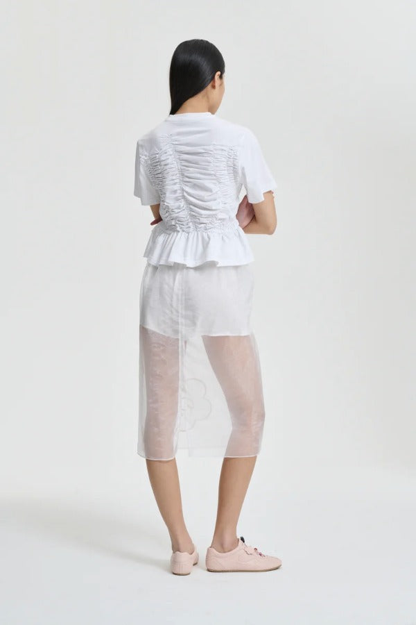Back view of white ace t-shirt on model wearing white shorts and pink sneakers, against a white background.
